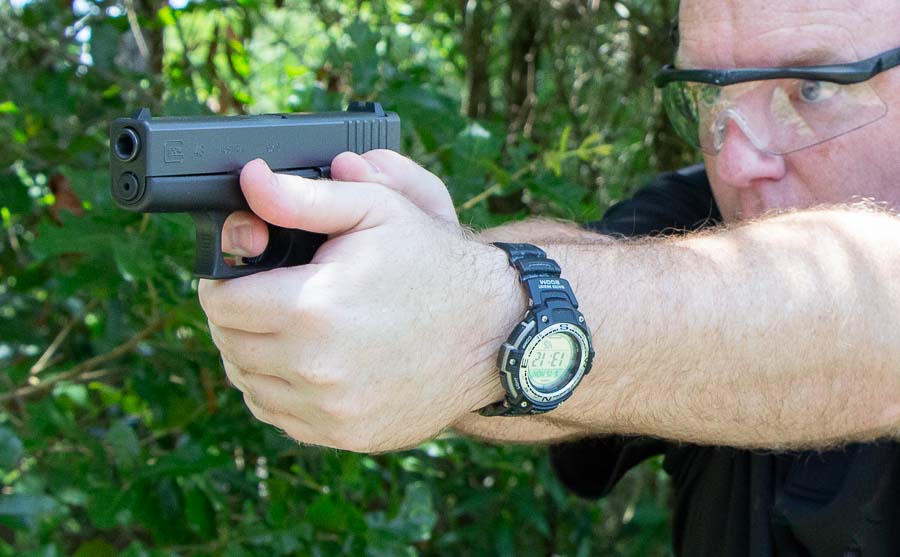 In this photo, the author is shooting the Glock 43 with a two handed grip. The author, Richard Johnson, is a gun writer. He is an adult male human referred to as a man. The gun was released at the NRA Annual Meeting & Exhibits and not the SHOT Show.