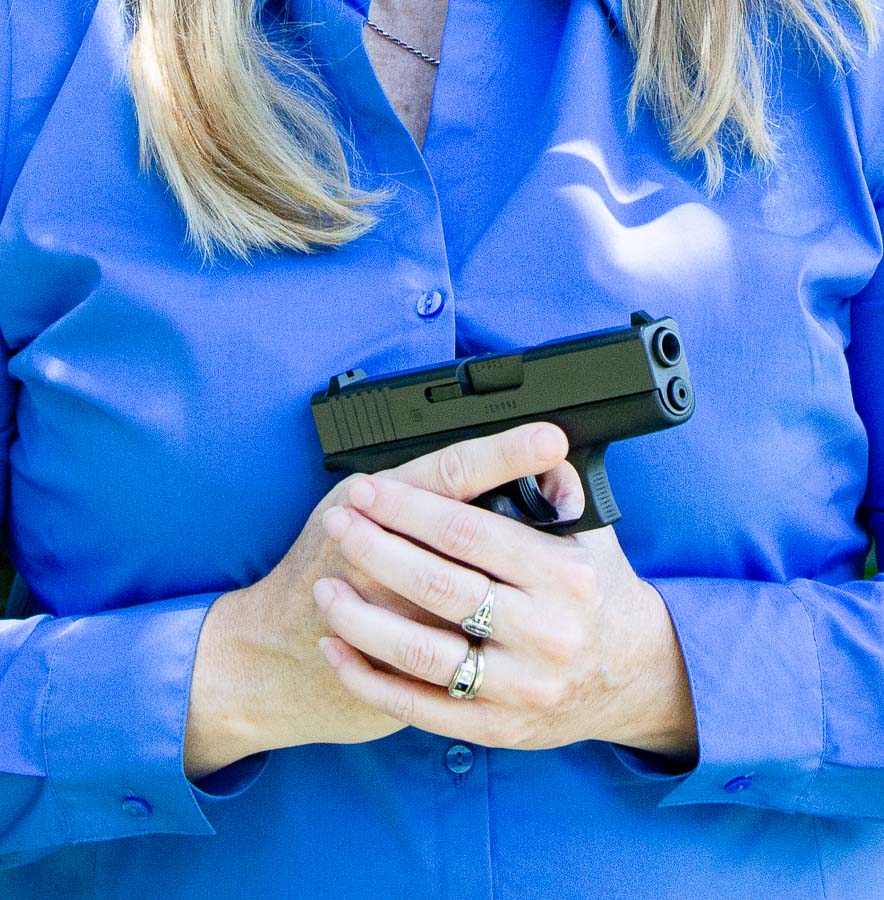 In this picture, the adult female human is holding the Glock 43 handgun in her right hand. She exhibits good safety skills with her trigger finger aligned along the gun frame and the muzzle pointed in a safe direction. 