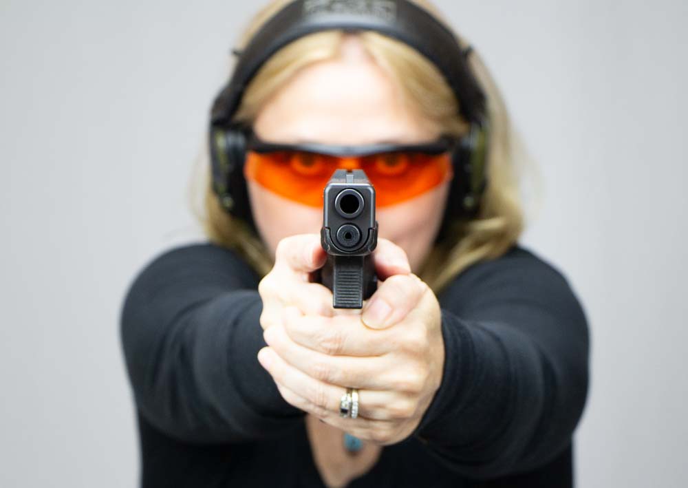 In this photo we see a blonde woman shooting the Glock 17 Gen 4 9mm pistol on the shooting range. The Glock 17 was the first semi-automatic handgun designed by Gaston Glock. Gaston Glock was an Austrian engineer and businessman. He founded the company Glock and developed the Glock pistol in 1982, which became one of the most influential and popular light firearms of the 20th century.